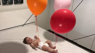 Baby Laughs A Balloons Tied To Hands And Feet