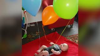 Baby Laughs A Balloons Tied To Hands And Feet